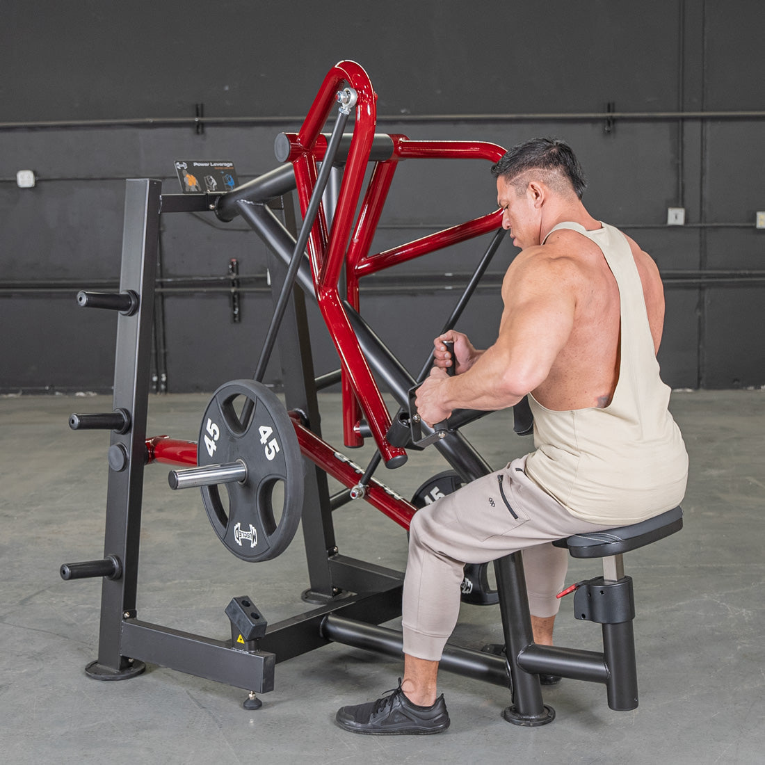 Man using red plate-loaded rowing machine in gym.