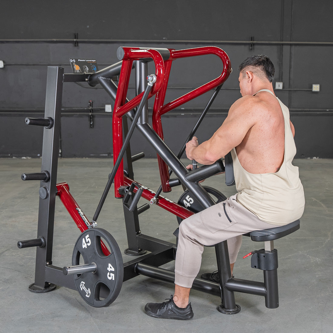 Man using Body-Solid leverage row machine with red frame in gym.