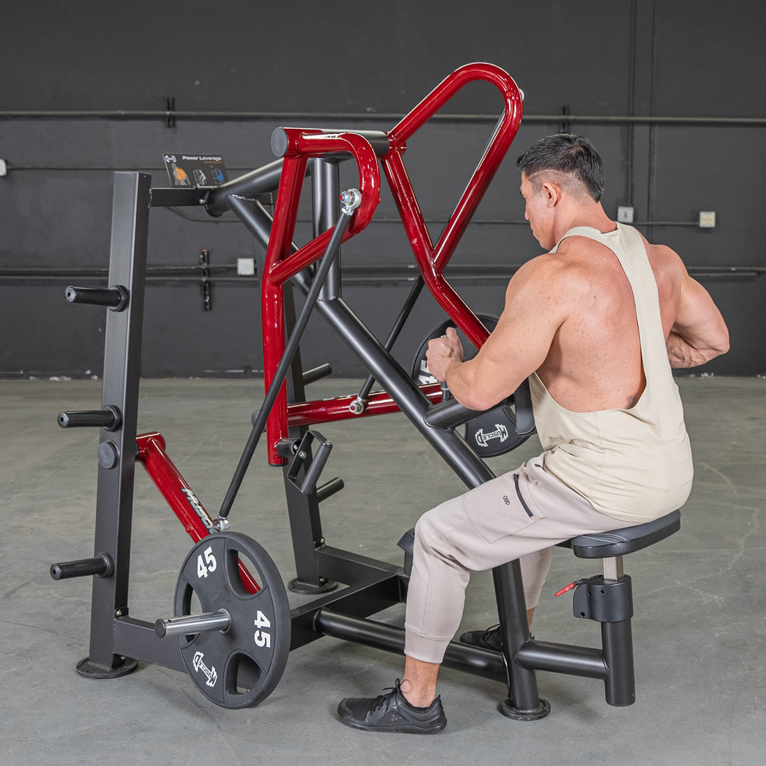 Man using Plate loaded row machine with red handles in gym.