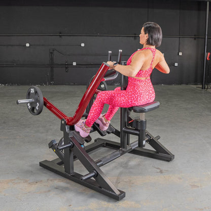 Woman in pink leopard print outfit using a red seated row machine in a gym.