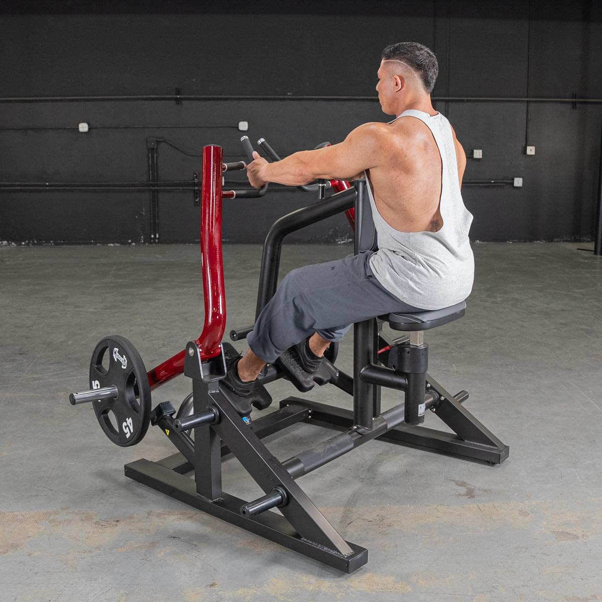Man using a seated row machine with red handles for back exercise in a gym.