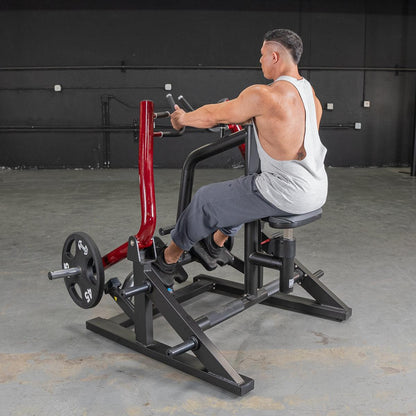Man using a seated row machine with red handles for back exercise in a gym.