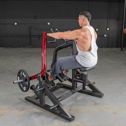 Man using a seated row machine with red handles, wearing a gray tank top in a gym setting.