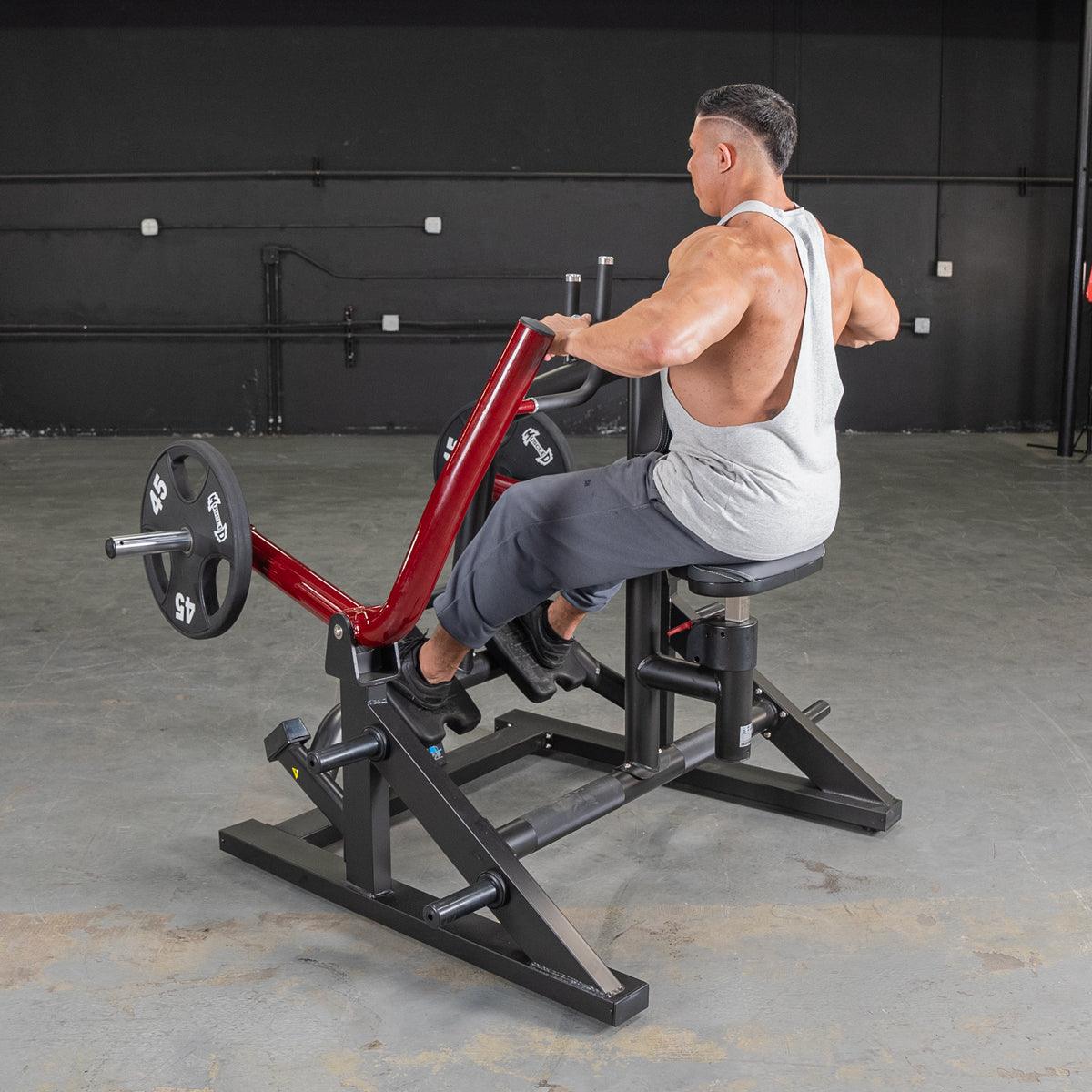 Man using red seated row machine in gym for back workout.