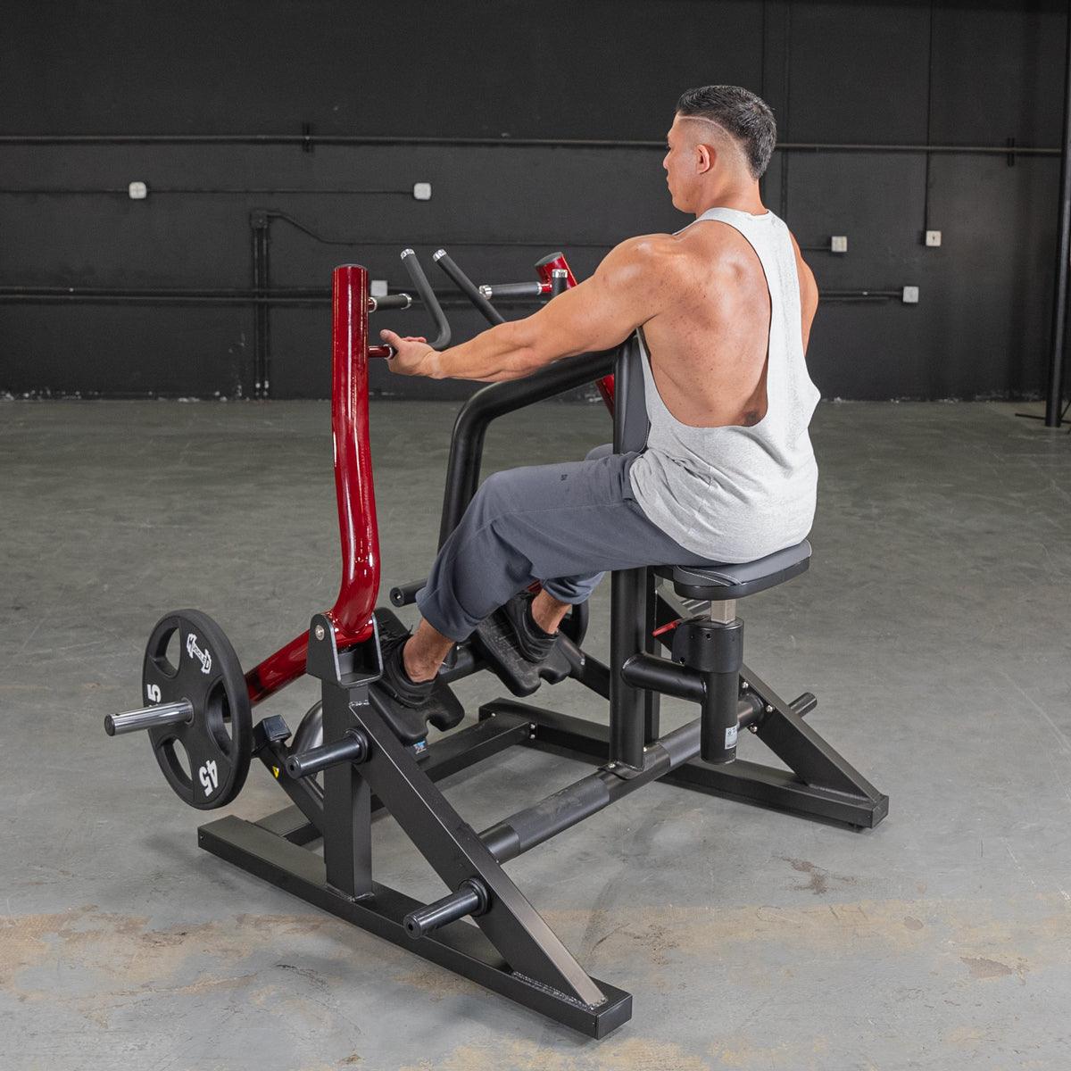 Man using seated row machine with red handles in gym for back workout.