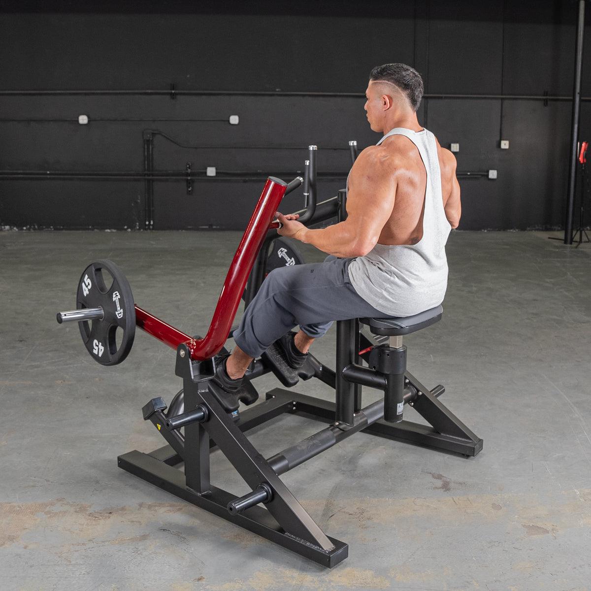 Man using a red seated row machine for back workout in gym.