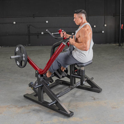 Man using a seated row machine with red handles in a gym.