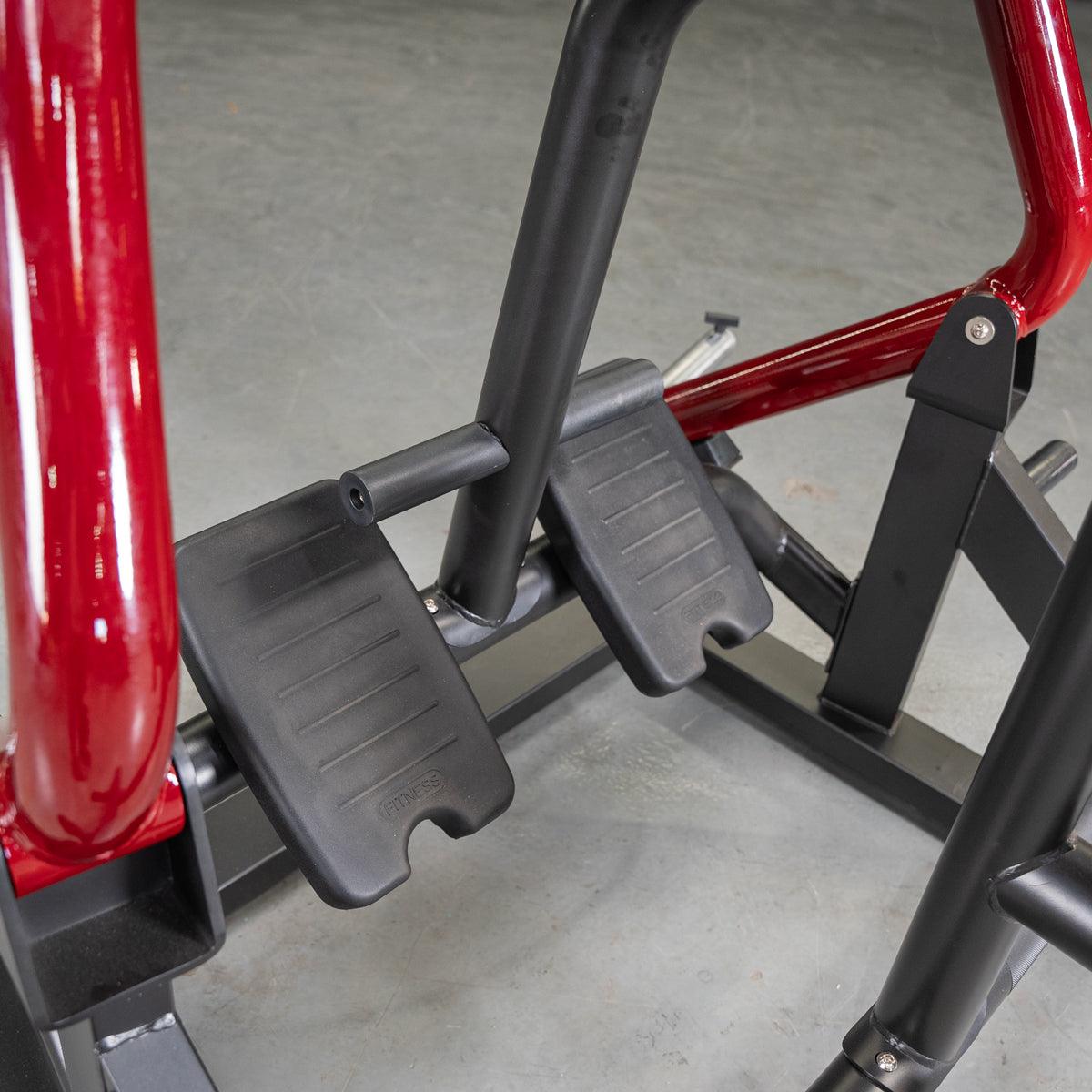 Gym equipment with red steel frame and black foot pedals for strength training.