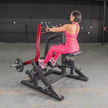 Woman in pink leopard print workout outfit using seated row machine in gym.