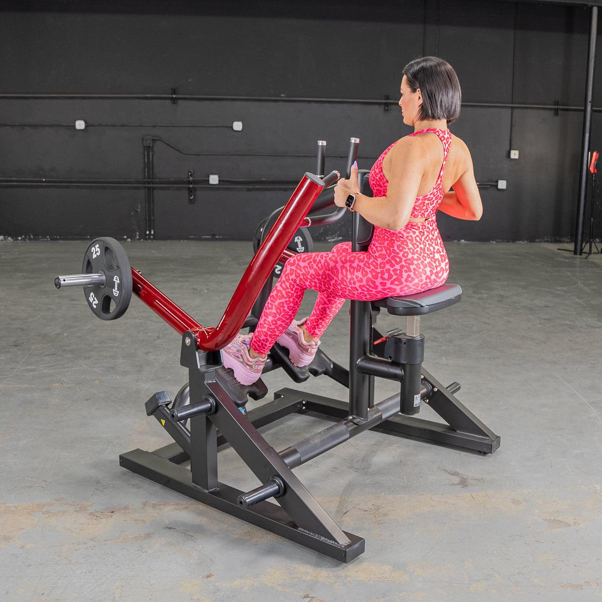Woman using red seated row machine in pink leopard print workout outfit.