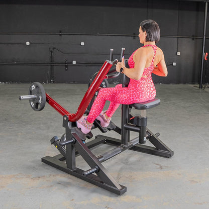 Woman using red seated row machine in pink leopard print workout outfit.