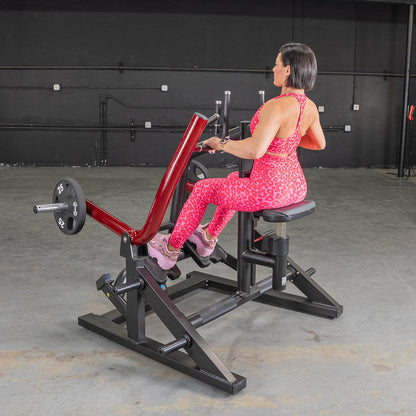 Woman in pink leopard print workout set using a seated row machine in a gym.