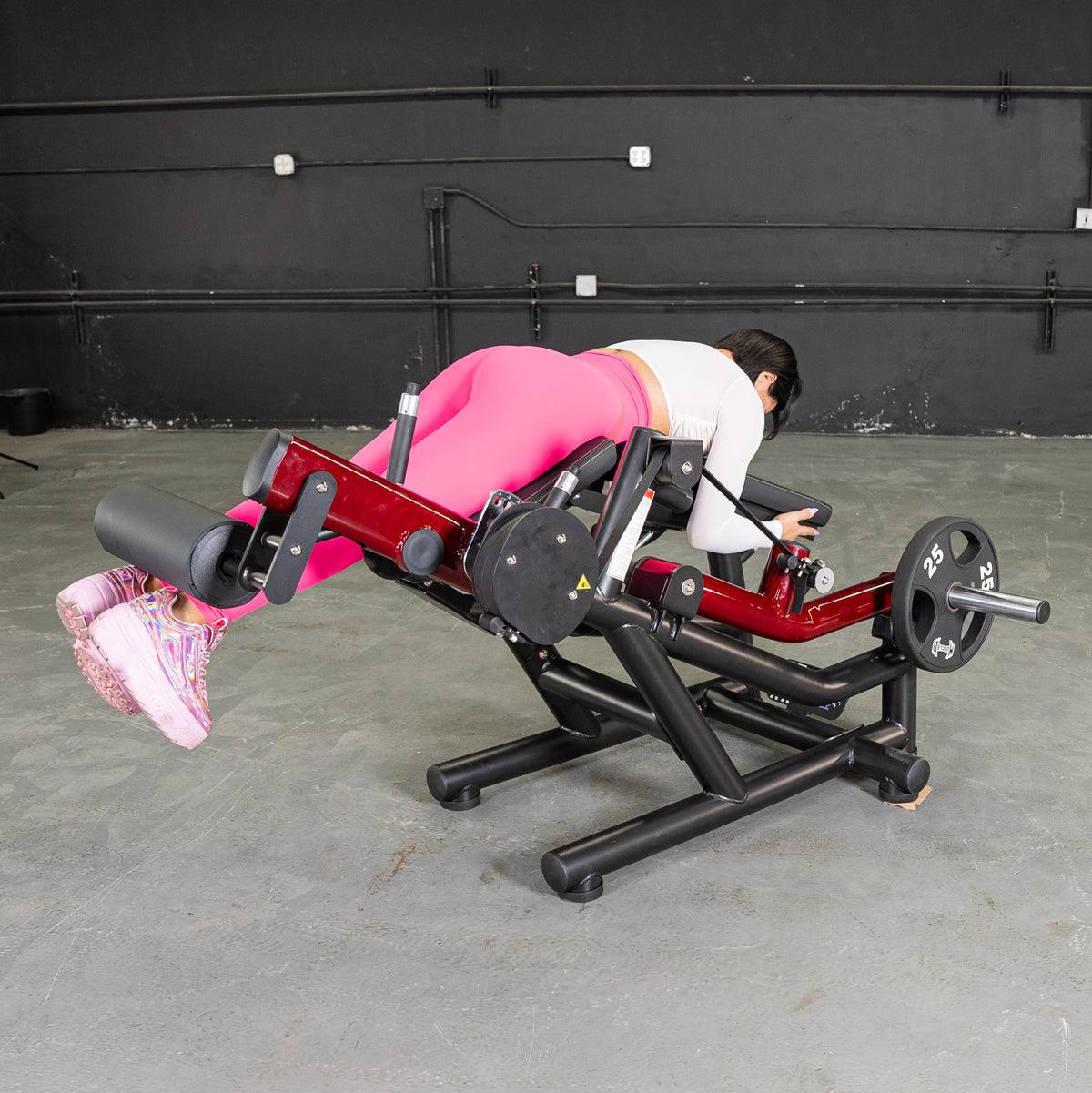 Person in pink leggings using a Power Lever V2 leg extension/prone leg curl machine.