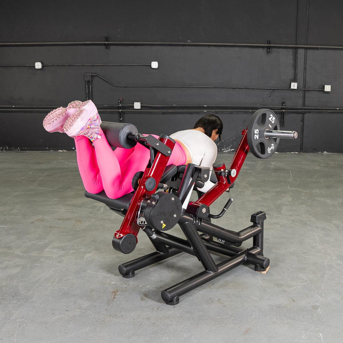 Person on leg extension/prone leg curl machine wearing pink leggings.