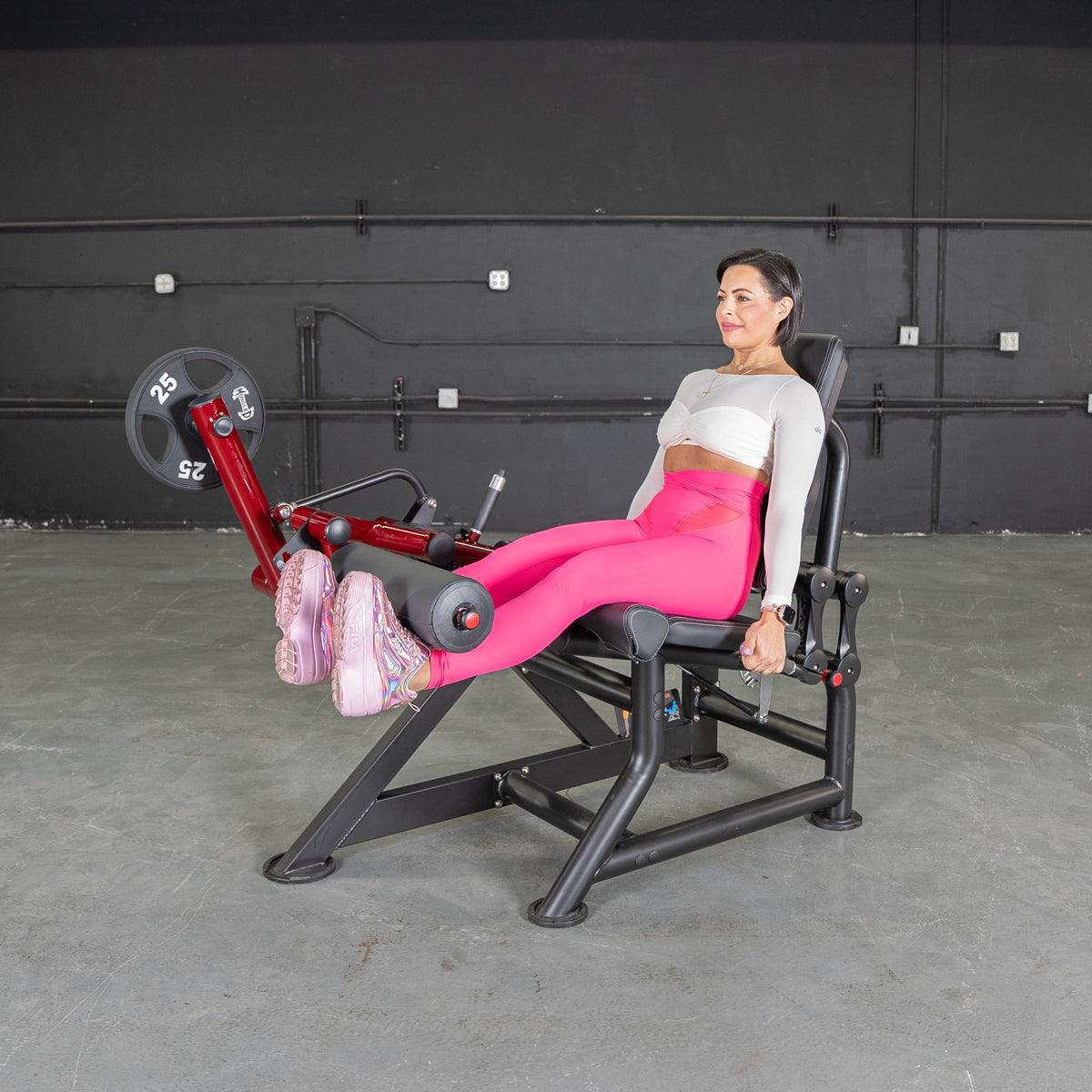 Woman seated on Power Leverage leg extension machine in gym.