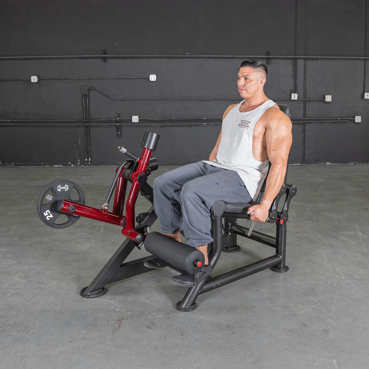 Man seated on Power Leverage V2 leg extension machine at gym.