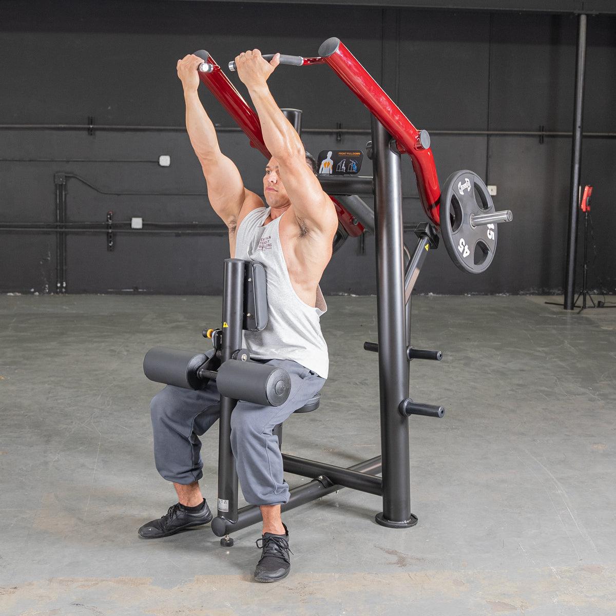 Man using a red shoulder press machine in the gym for strength training.
