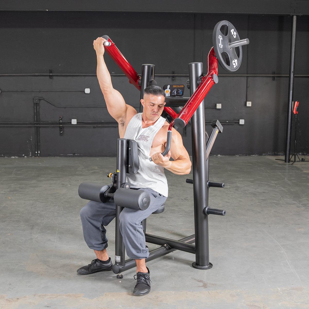 Man using red shoulder press machine in gym.