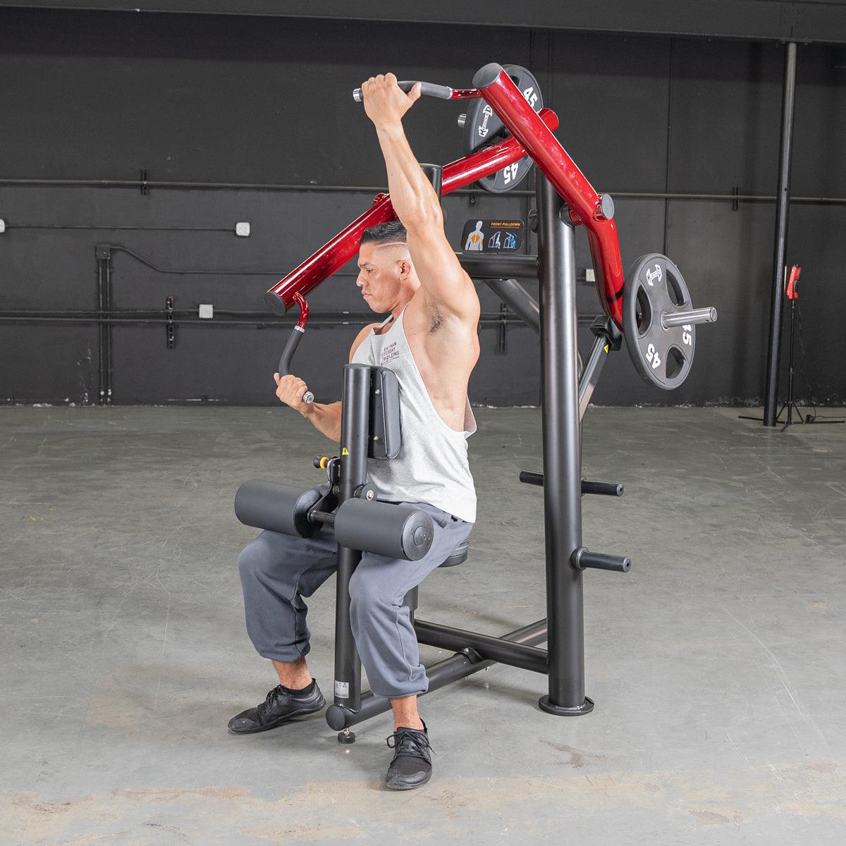 Man using red seated shoulder press machine in gym.