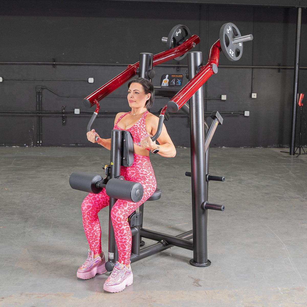 Woman in pink leopard print workout gear using red chest press machine in gym.