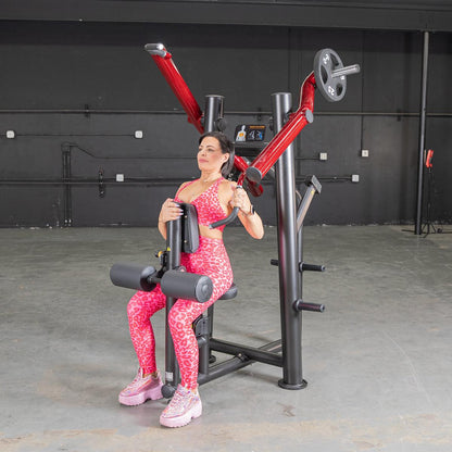 Woman in pink leopard workout set using a red chest press machine in gym.