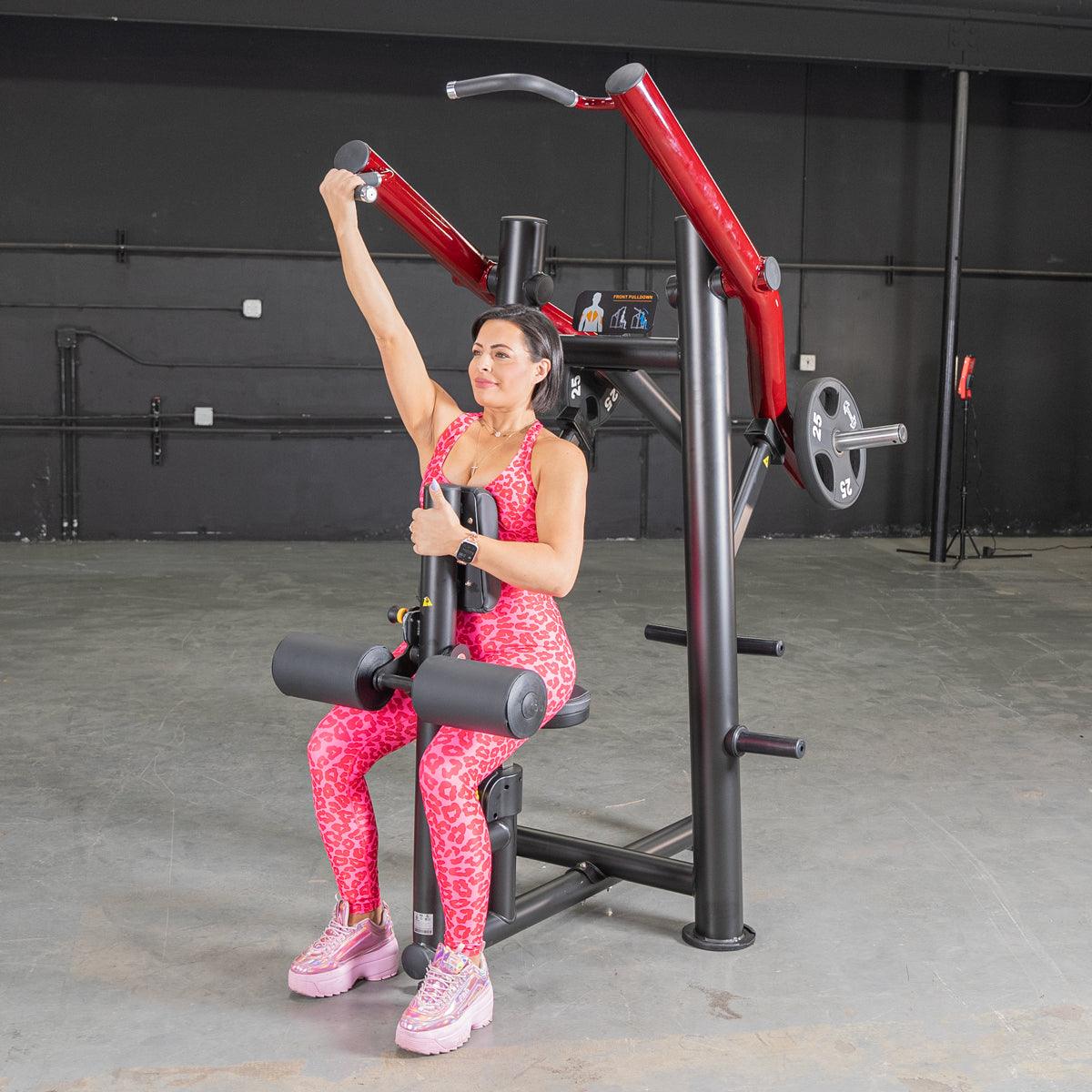 Woman in pink leopard print workout gear using a seated arm press machine in a gym.