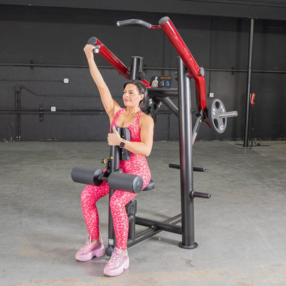 Woman in pink leopard print workout gear using a seated arm press machine in a gym.