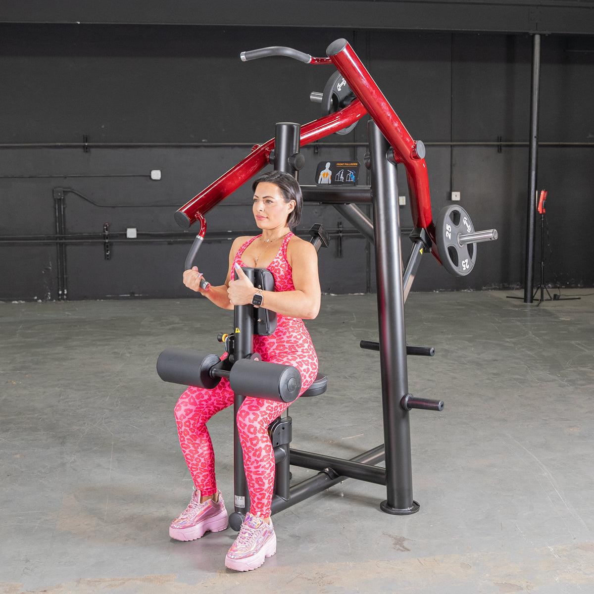 Woman using a red chest press machine in a gym, wearing pink leopard print activewear.
