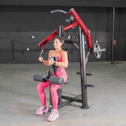 Woman using a red chest press machine in a gym, wearing pink leopard print activewear.