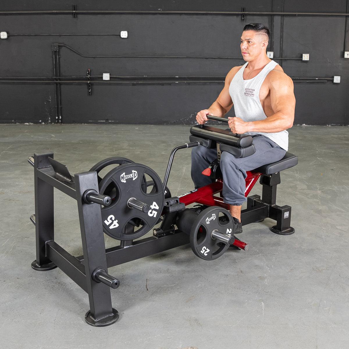 Man using a seated calf raise machine with weights in a gym.
