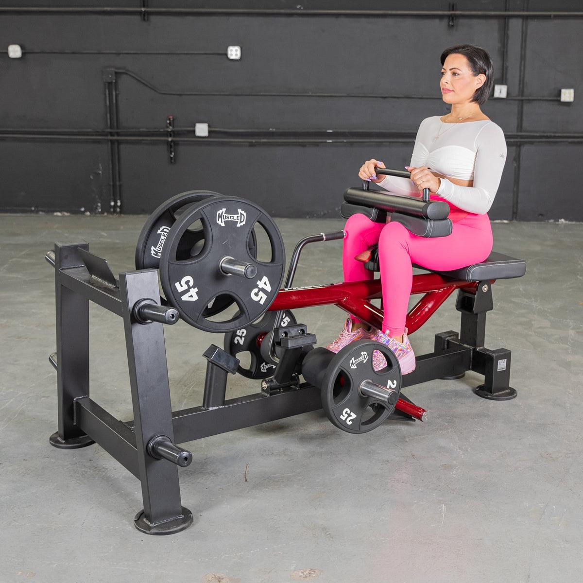 Woman seated on a calf raise machine with weight plates.