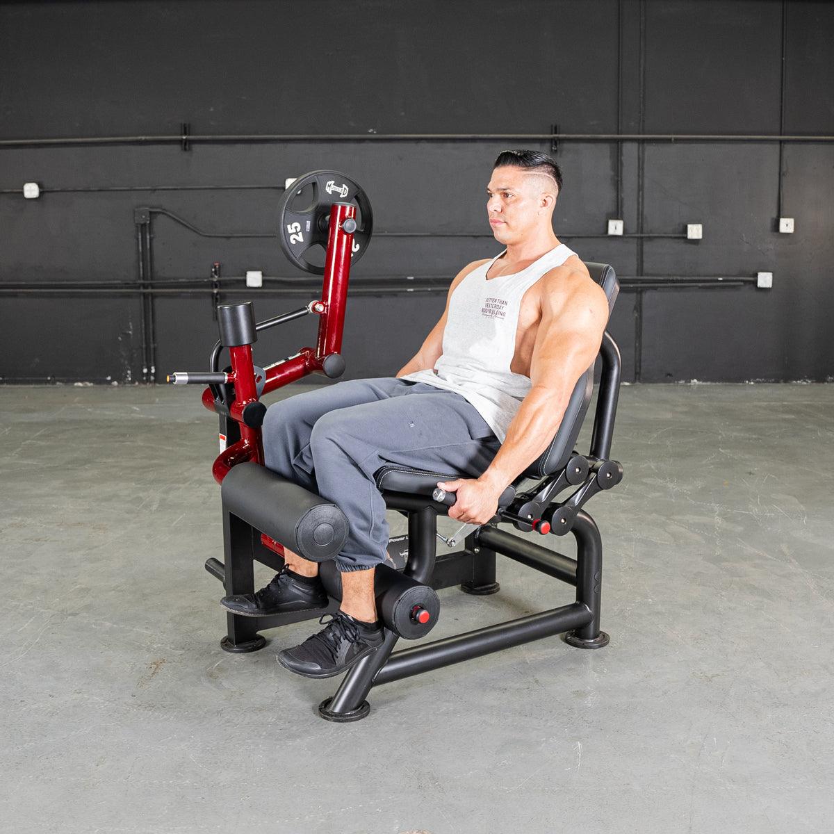 Man seated on leg-curl machine in a gym.