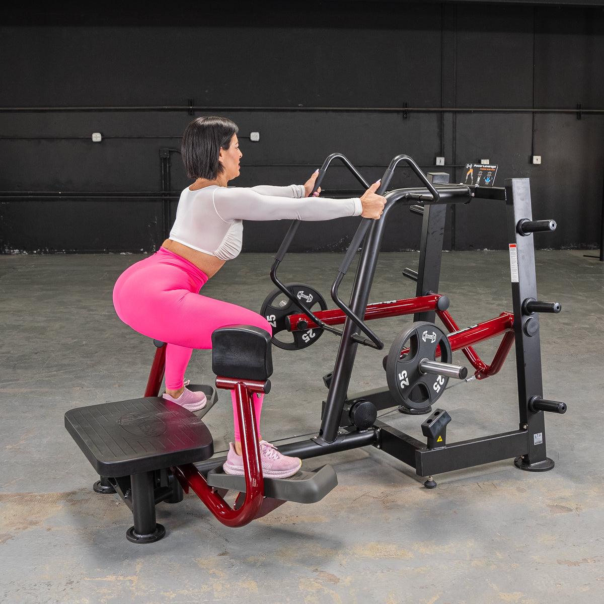 Woman in pink leggings uses Power Leverage Standing Abductor machine at gym.