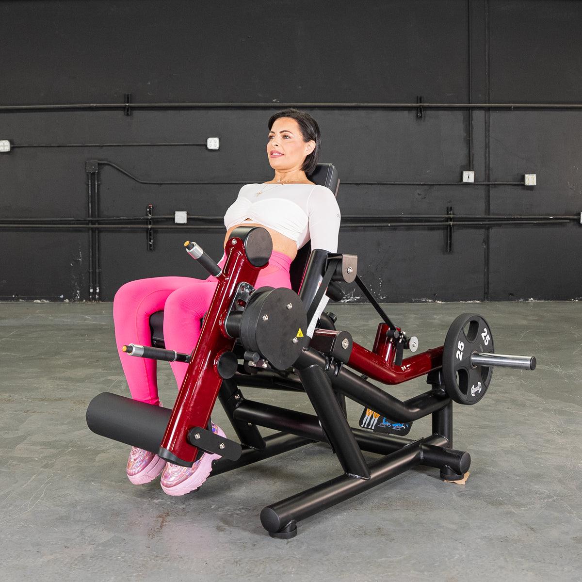 Woman seated on Power Leverage V2 leg extension and prone leg curl combo.