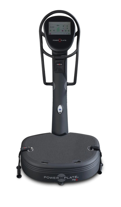 Black Power Plate vibration platform with digital display console mounted on handlebar frame, showing timer at 0:30. Large gray platform base with control buttons on sides.