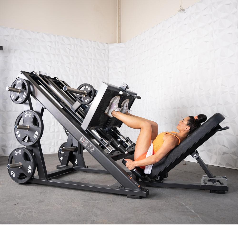 Woman using ProStrength dual leg press machine with weighted plates.
