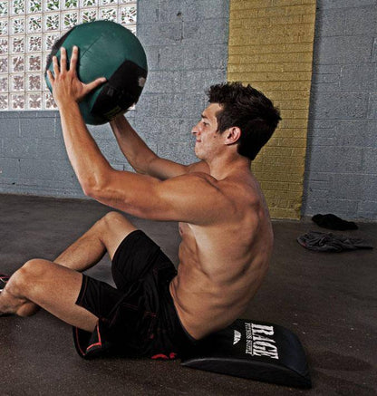 Man exercising with a medicine ball against a brick wall.