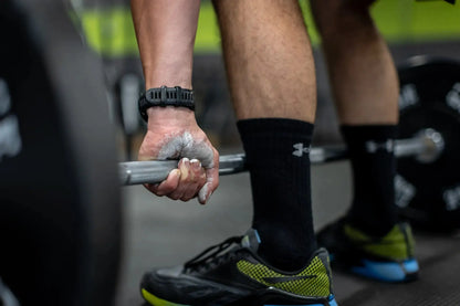 Close-up of chalk-dusted hands gripping a barbell in a gym.