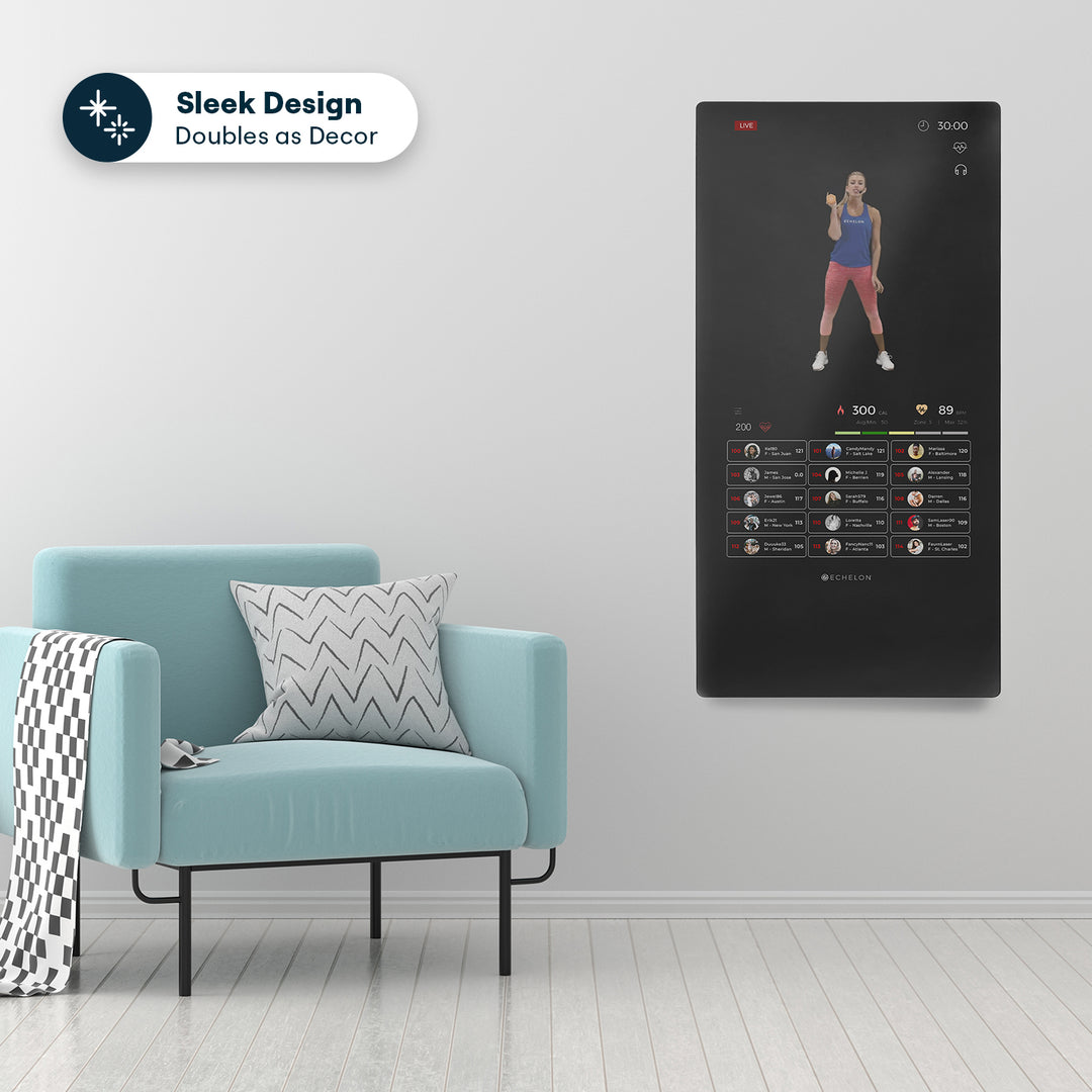 Echelon Reflect 50 Smart Fitness Mirror mounted on a wall, displaying a workout interface, alongside a modern light blue chair with a patterned pillow and throw blanket.