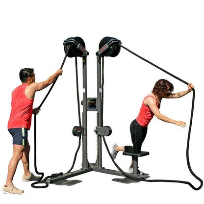 Two people in red tank tops using a dual battle rope trainer for fitness exercise.