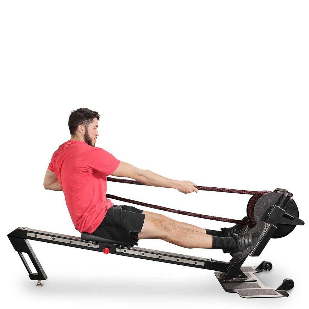 Man exercising on black rowing machine in red shirt, focusing on fitness.