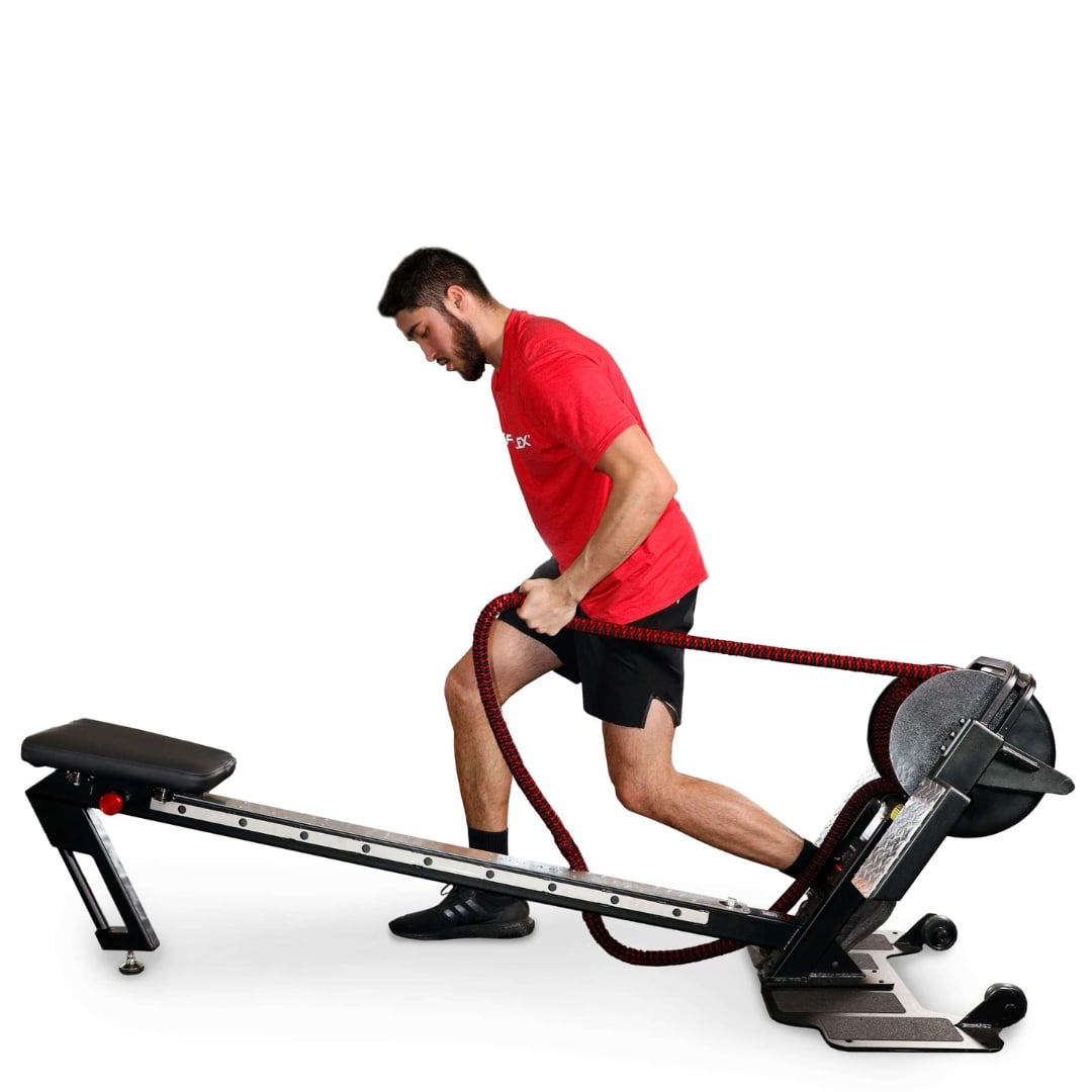 Man exercising on a SkiErg in a red shirt and black shorts, pulling a resistance rope.