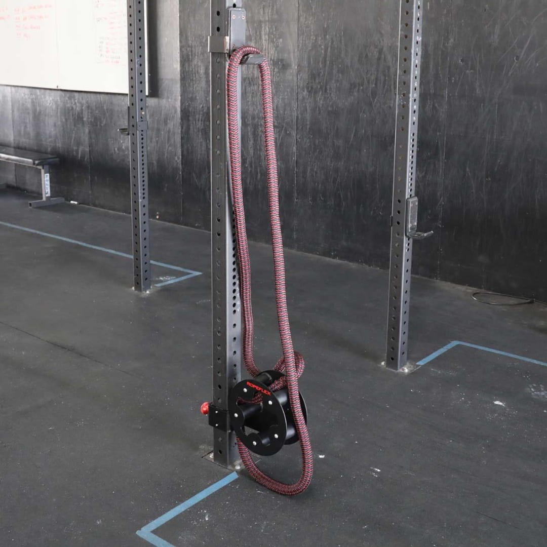 Heavy-duty battle rope anchor with red rope in a gym.