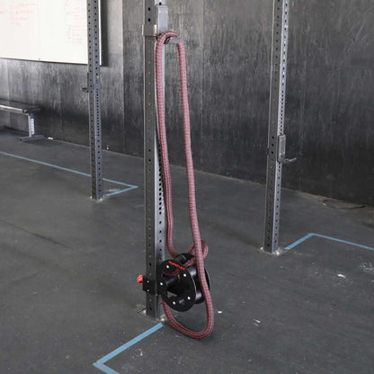 Heavy-duty battle rope anchor with red rope in a gym.