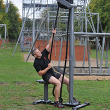Man using rope climbing exercise machine outdoors for fitness training.