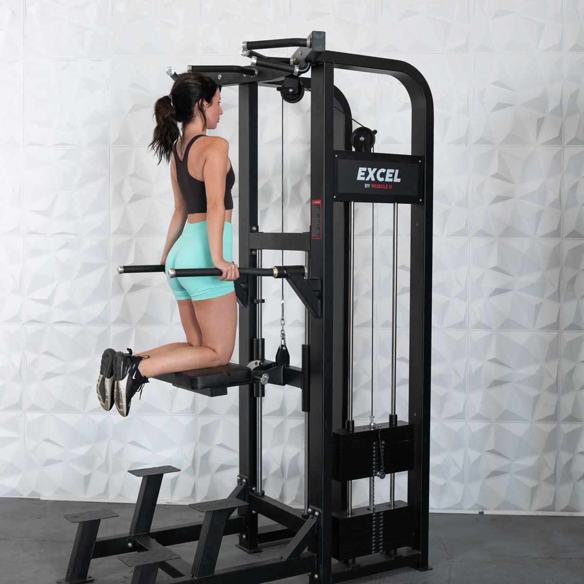 Woman using Excel dip machine for tricep exercise in gym.