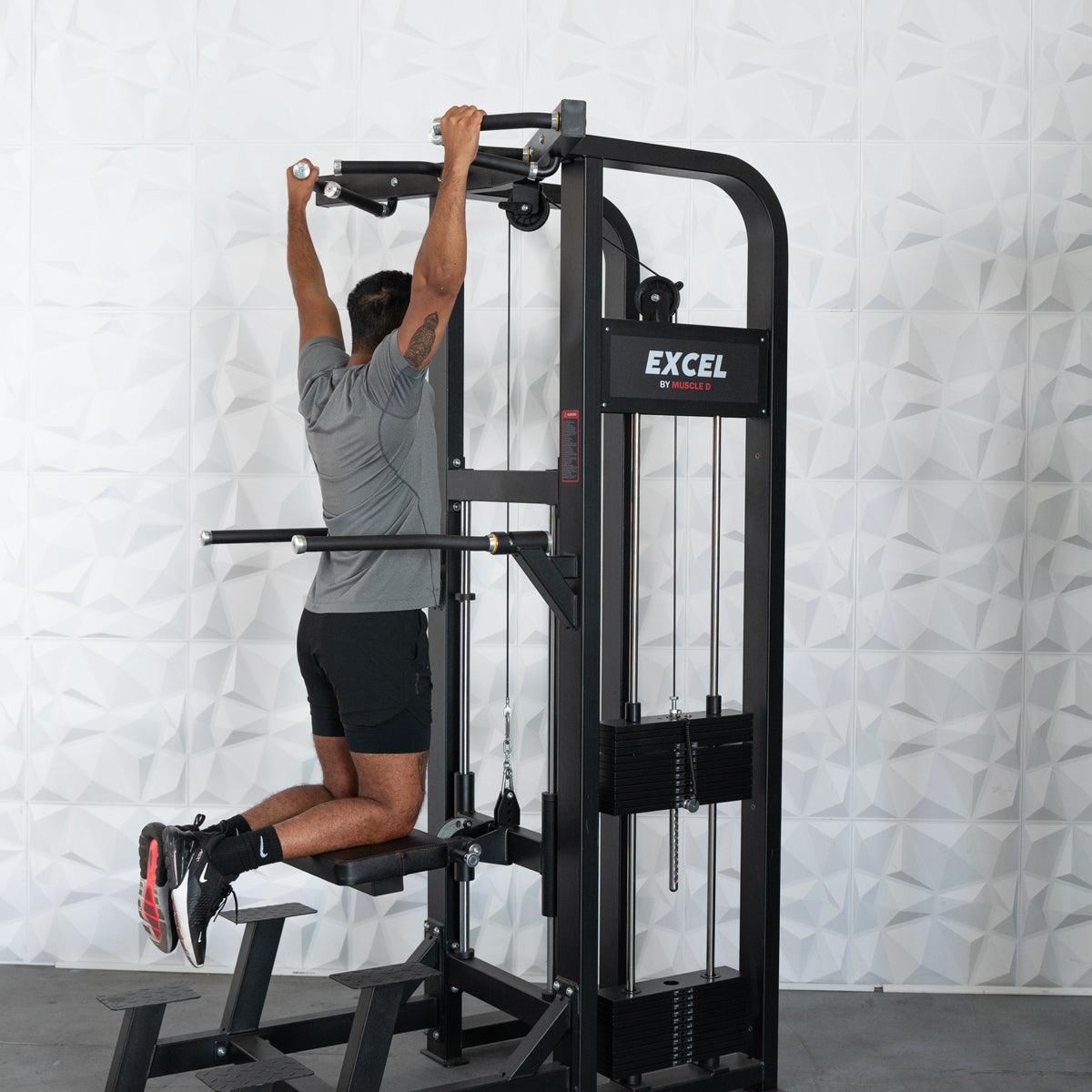 Man using Excel pull-up machine with padded knee support.