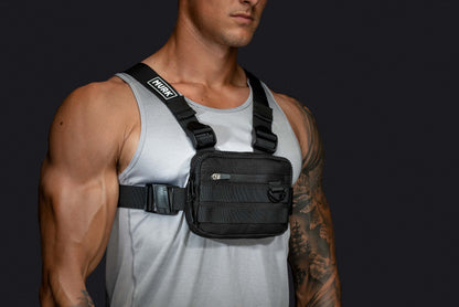 Athletic man wearing a black tactical chest rig with a front pocket.