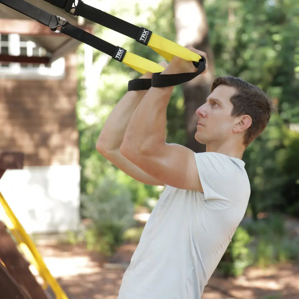 TRX Strong Suspension Trainer – black straps hanging vertically with padded handles ready for use