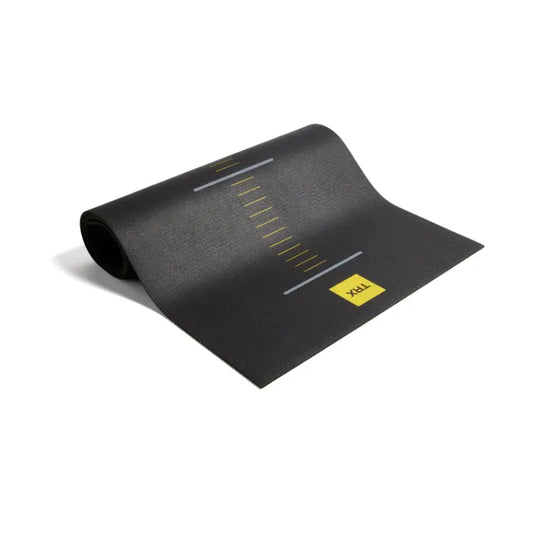 TRX suspension training mat rolled up; black with yellow TRX logo and measurement marks.